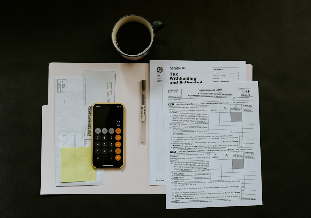 Tax withholding certificate on a folder beside a pen and smartphone